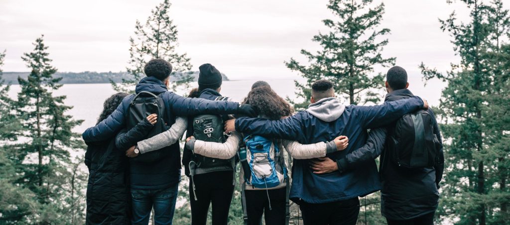 Friends embrace while standing on a scenic cliff, symbolizing unity and adventure.